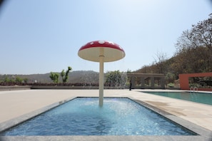 Une piscine agrémentée d’une fontaine centrale en forme de champignon.