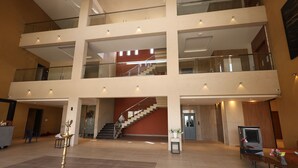 Un amplio atrio con una escalera central, varios balcones y una zona de recepción con una máquina de café.