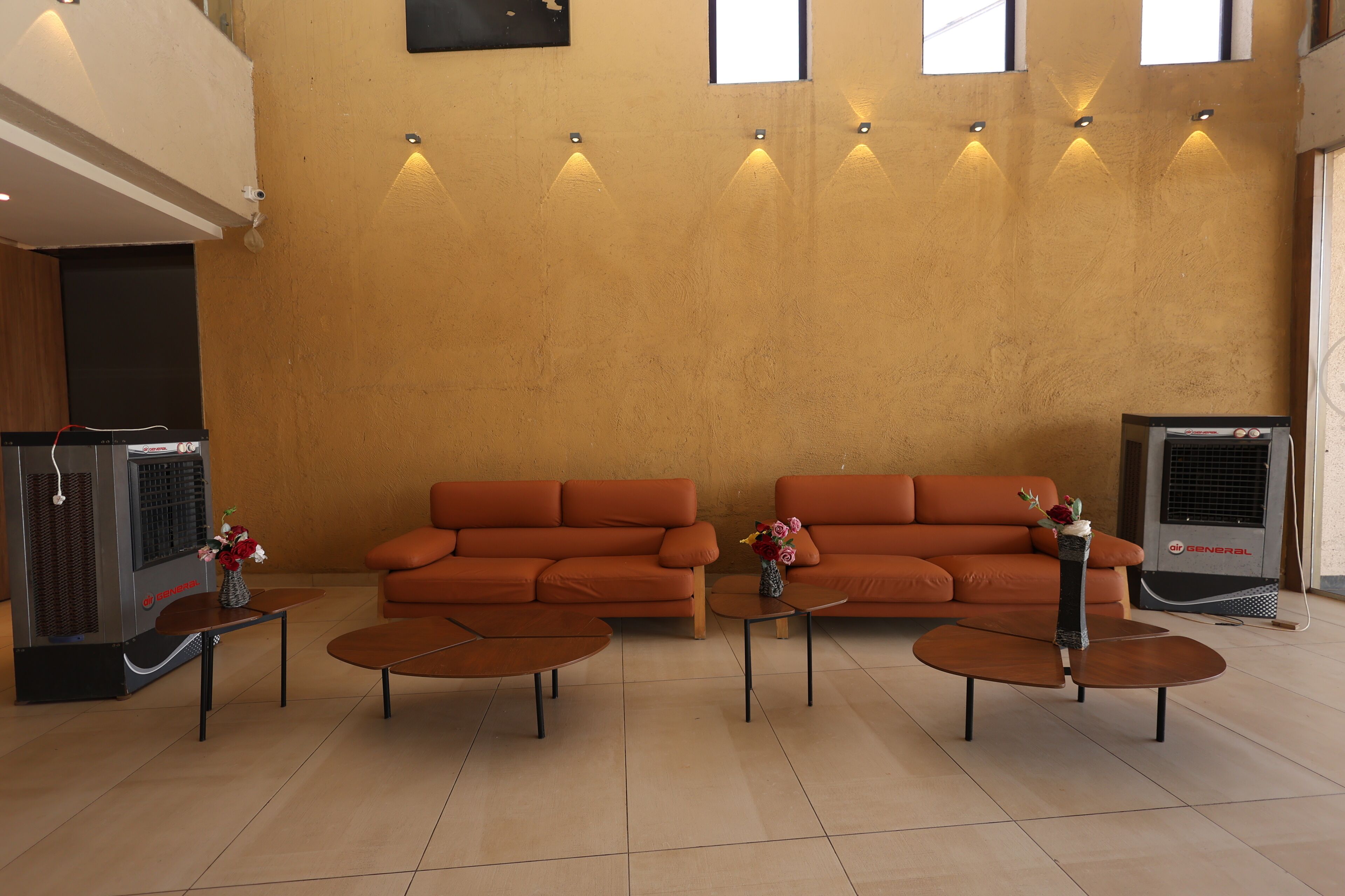 A modern living area with two sofas, two coffee tables, and a decorative vase.