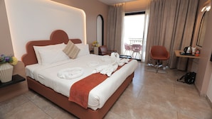 Una habitación de hotel moderna con una cama grande, un área de estar con una silla, una mesita y vistas al balcón.