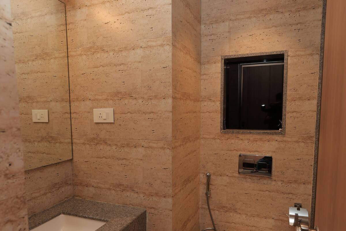 A bathroom with a marble sink, a toilet, and a small window.