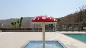 Una piscina con una fuente de agua con forma de hongo.