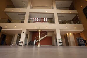 A multi-level interior with a central staircase, glass railings, and a decorative brass object. - Ripples Resort (Malkhed)