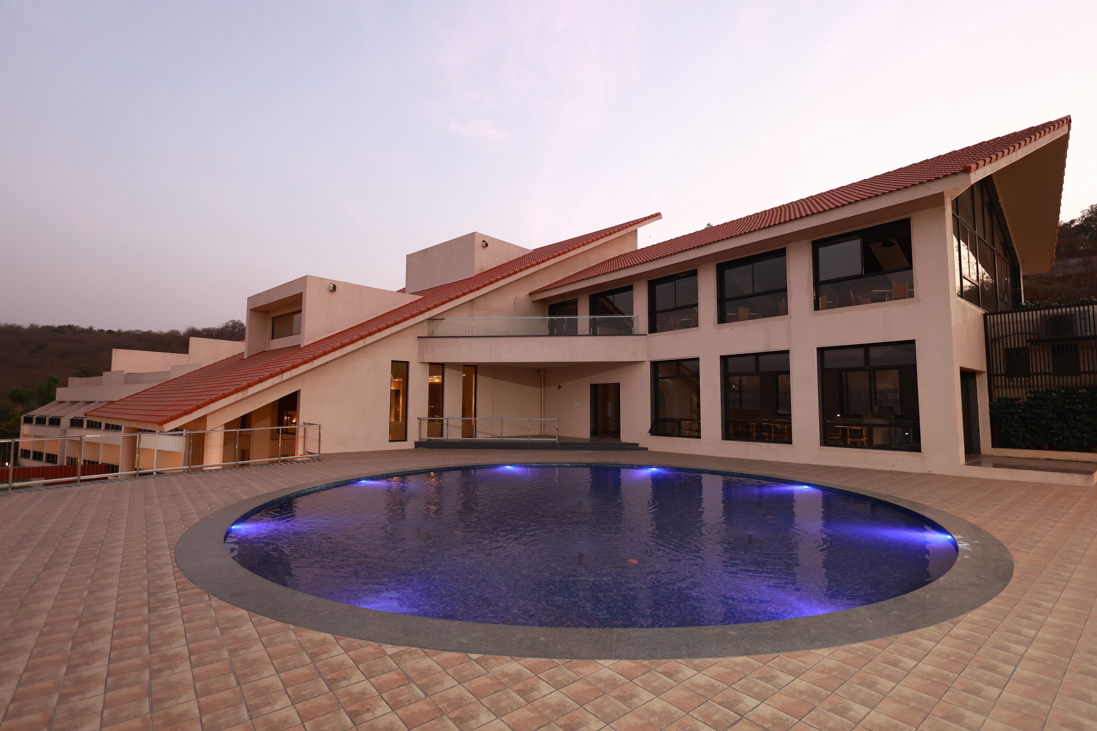 A modern building with a swimming pool, large windows, and a sloped roof.