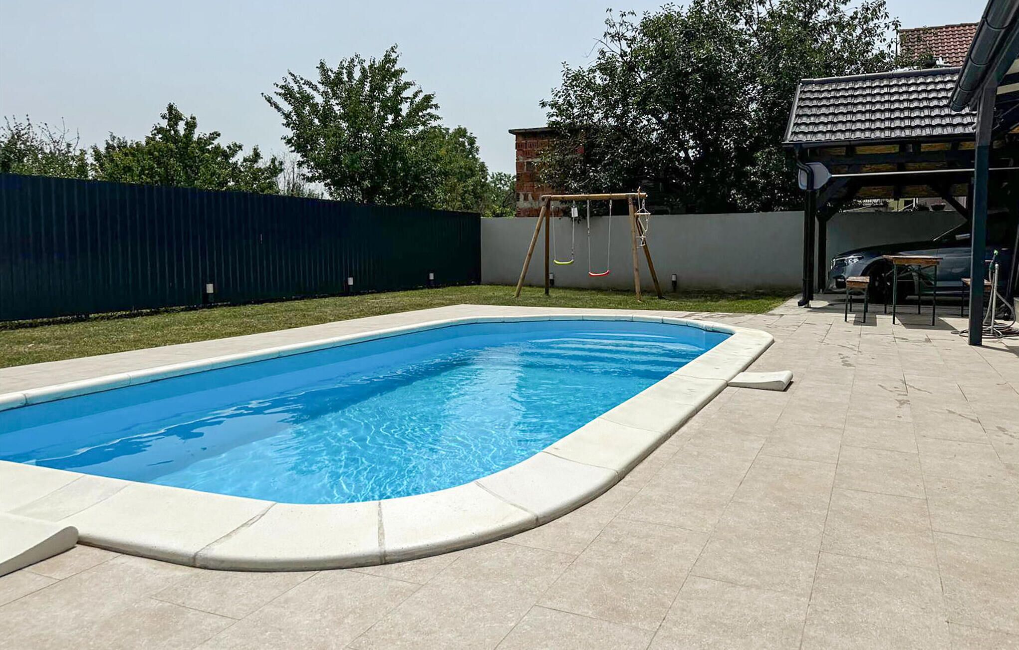 Ein rechteckiger Pool mit einer gefliesten Terrasse rundherum.