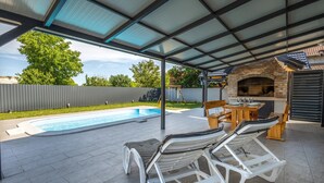 A covered outdoor area with a pool, lounge chairs, and a brick oven. - Luxurious home in Vukovar (Vukovar)