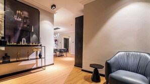 En moderne stue med en lædersofa, en glasmontre og et spiseområde i baggrunden.