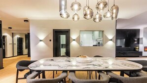 Et moderne spiseområde med et marmorbord, seks stole og hængende lamper.