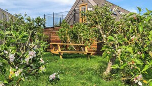 A rustic wooden house with a sloped roof, a visible chimney, and a metal fence. - 1 bedroom accommodation in near Uppingham (near Uppingham)