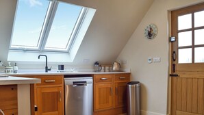 A kitchen with wooden cabinets, a stainless steel dishwasher, a trash can, and a skylight. - 1 bedroom accommodation in near Uppingham (near Uppingham)