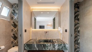 Un baño moderno con lavamanos de mármol, inodoro y ducha.