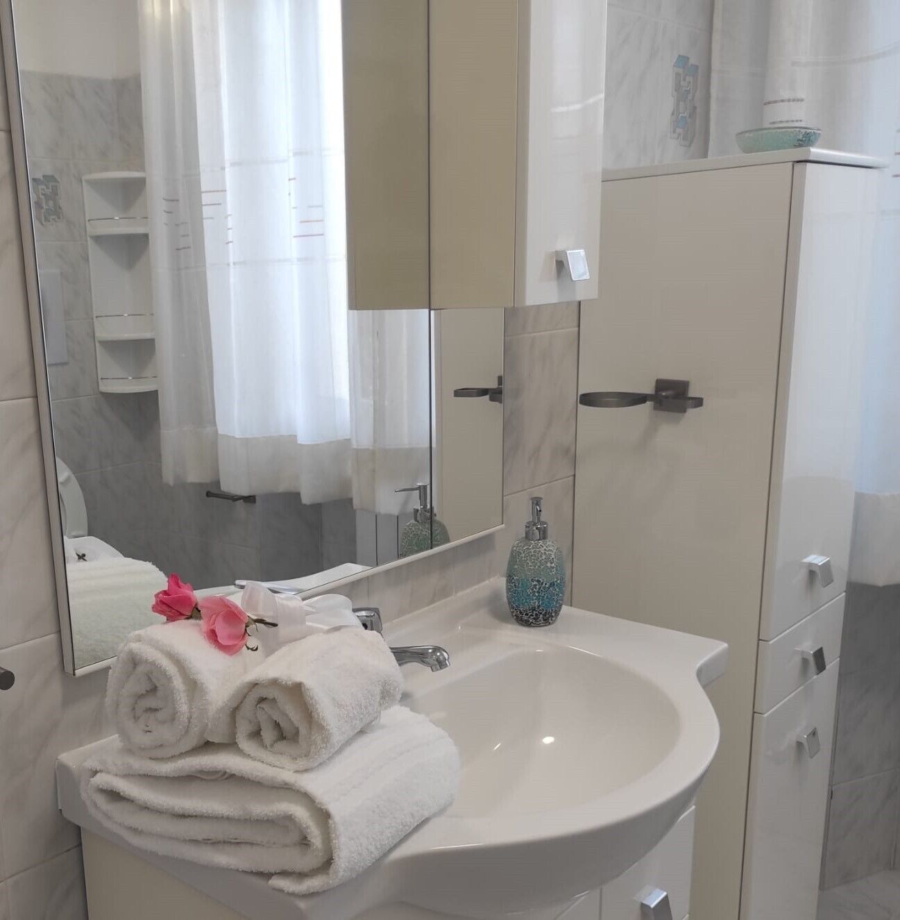 A bathroom with a white sink, a mirror, and a towel rack.