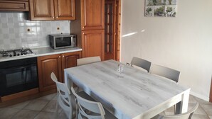 A kitchen with wooden cabinets, a microwave, a gas stove, and a dining table with chairs. - Accommodation near Assisi. Located in the countryside for a relaxing stay (Tordandrea di Assisi)