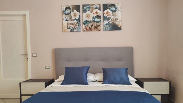 A bedroom with a bed, two nightstands, and a wall-mounted painting. - Accommodation near Assisi. Located in the countryside for a relaxing stay (Tordandrea di Assisi)