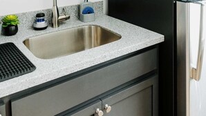 Een moderne keuken met een roestvrijstalen spoelbak, zwarte kastjes en een koelkast.