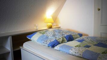 Une chambre à coucher avec un lit, une table de chevet, une lampe et une fenêtre.