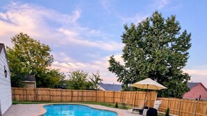 A backyard with a swimming pool and hot tub, surrounded by a wooden fence and a grassy lawn. - DFW Retreat • Pool, Spa & Minutes to Dallas & Fort Worth (Flower Mound)