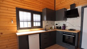 A compact kitchen with wooden walls, a built-in dishwasher, a stove, and a microwave.