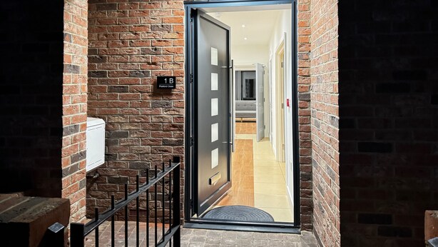 A brick exterior wall with a door labeled "1B Pickford Close."