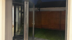 A sliding glass door leading to a covered outdoor area with artificial grass.
