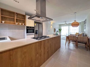 A modern kitchen with a central island, built-in oven, and stainless steel appliances.