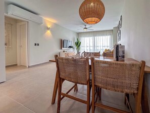 A modern dining area with wicker chairs, a round table, and a ceiling fan.