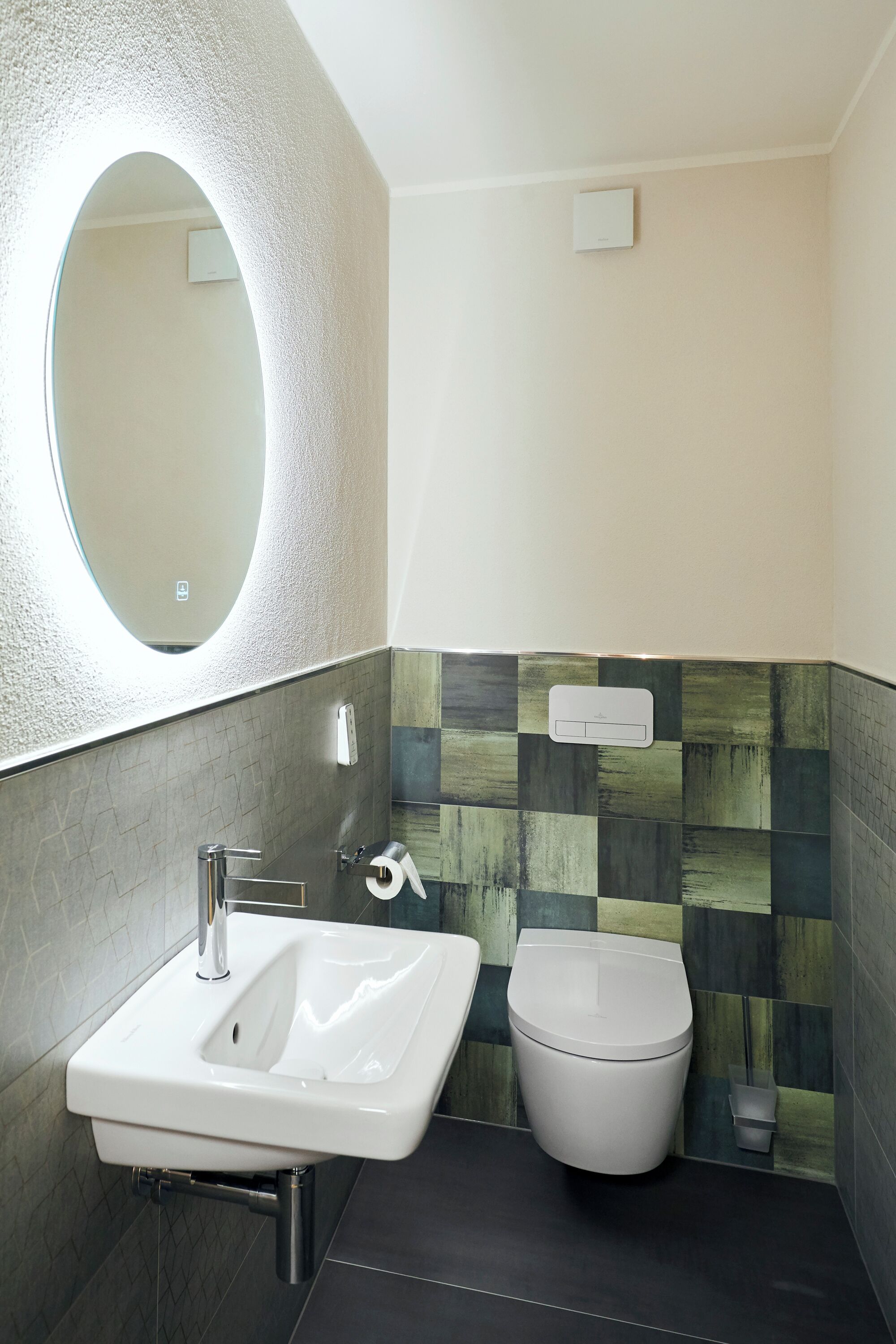 Un baño moderno con un lavamanos blanco, un inodoro y un espejo.