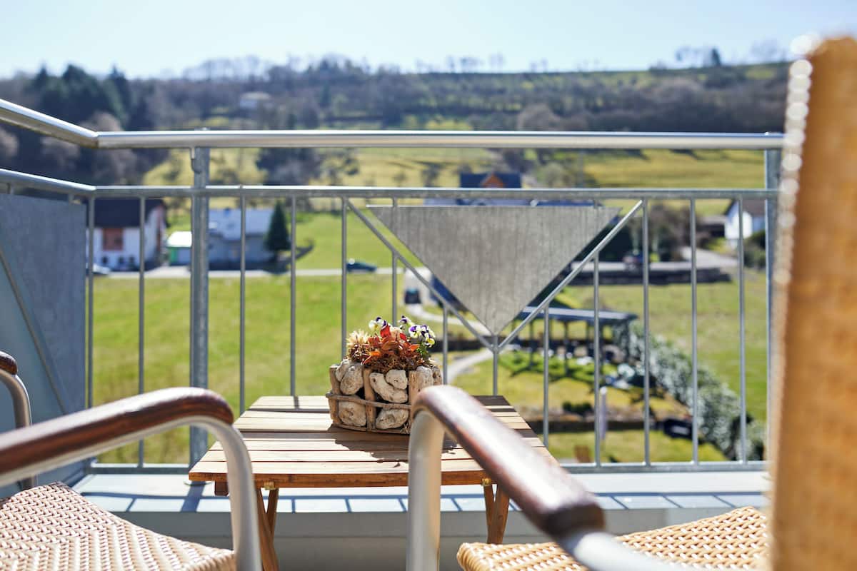 A balcony with wicker chairs, a wooden table, and a flower pot.