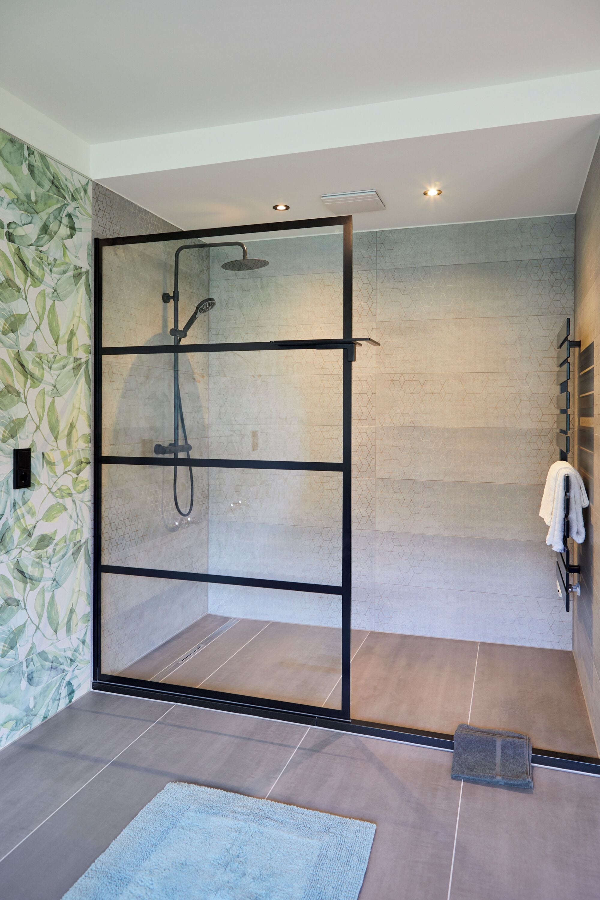 Une salle de bain moderne avec une douche à parois de verre, des murs carrelés et un porte-serviettes.