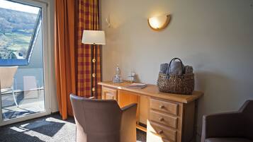Habitación de hotel con escritorio, dos sillas, lámpara, cesta y vista al exterior.