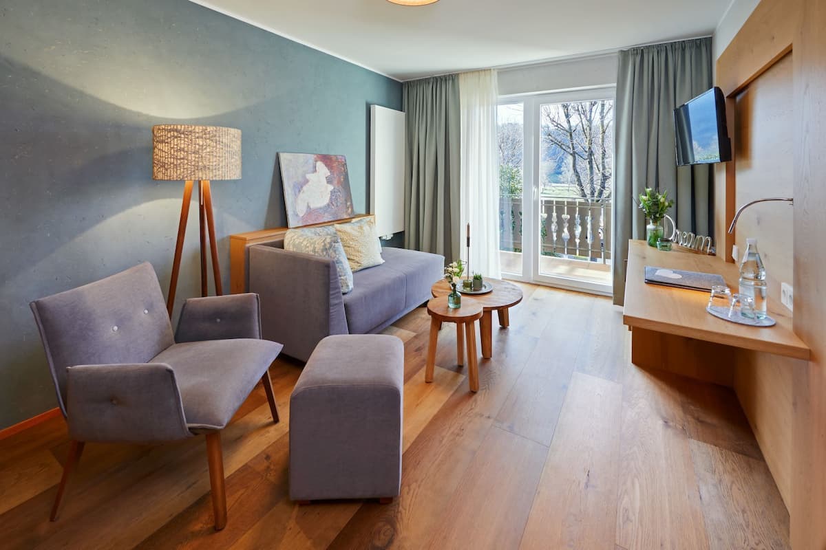 A modern living room with a sofa, two armchairs, a coffee table, and a TV mounted on the wall.