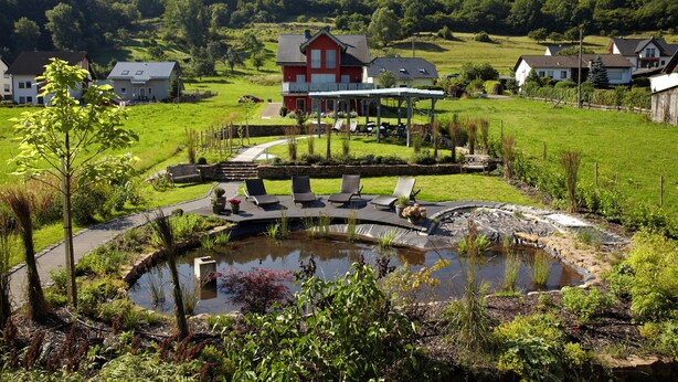A house with a pond, outdoor seating, and a garden. - NaturPur Hotel Maarblick (Meerfeld)