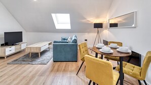 Un appartement moderne de style « loft », comprenant un coin repas, un canapé, un téléviseur et une fenêtre de toit.