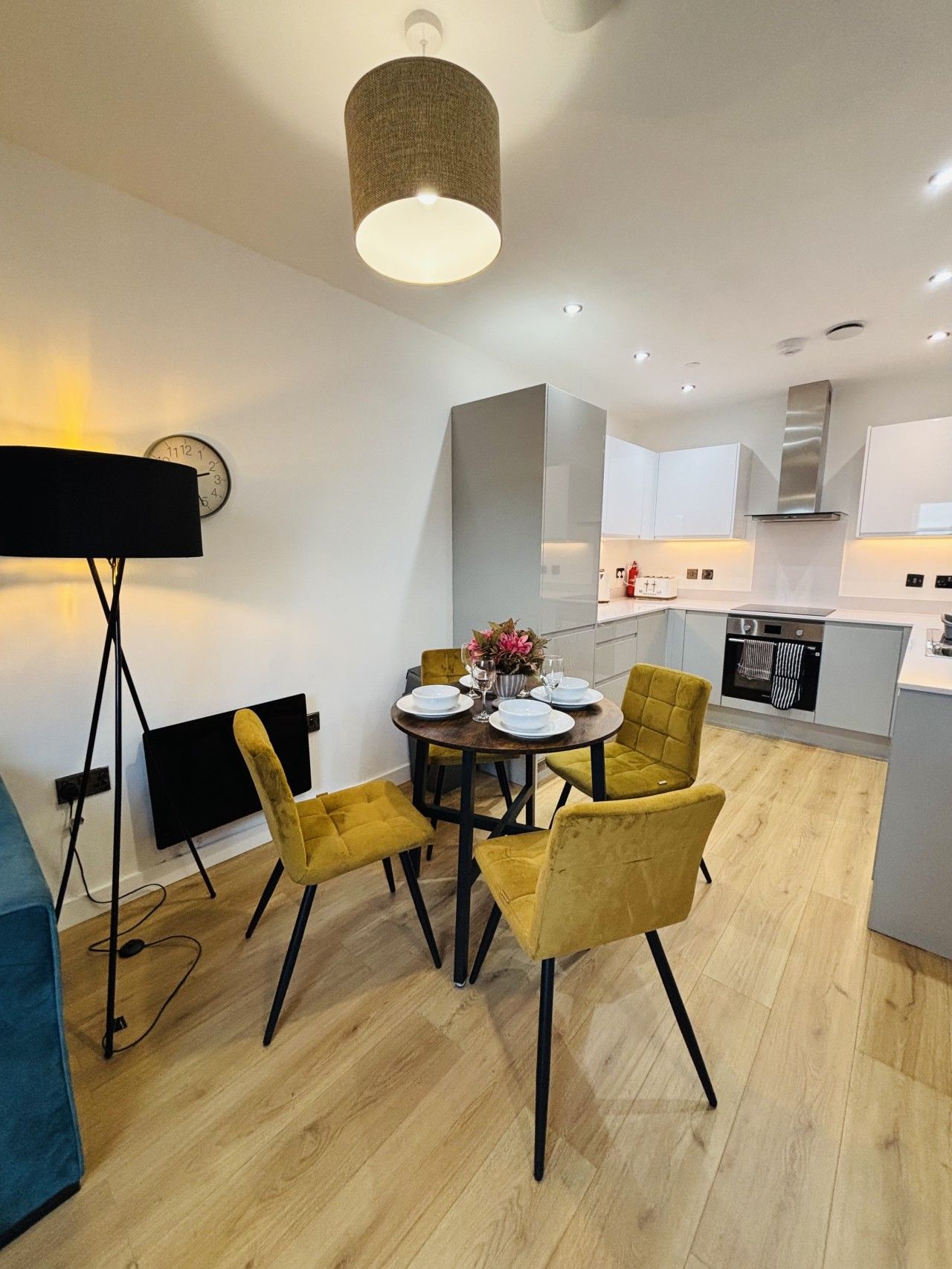 A modern kitchen with white cabinets, a stainless steel range hood, and a built-in oven.
