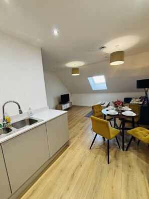 Una cocina moderna con lavamanos integrado y comedor con sillas amarillas y una mesa redonda.