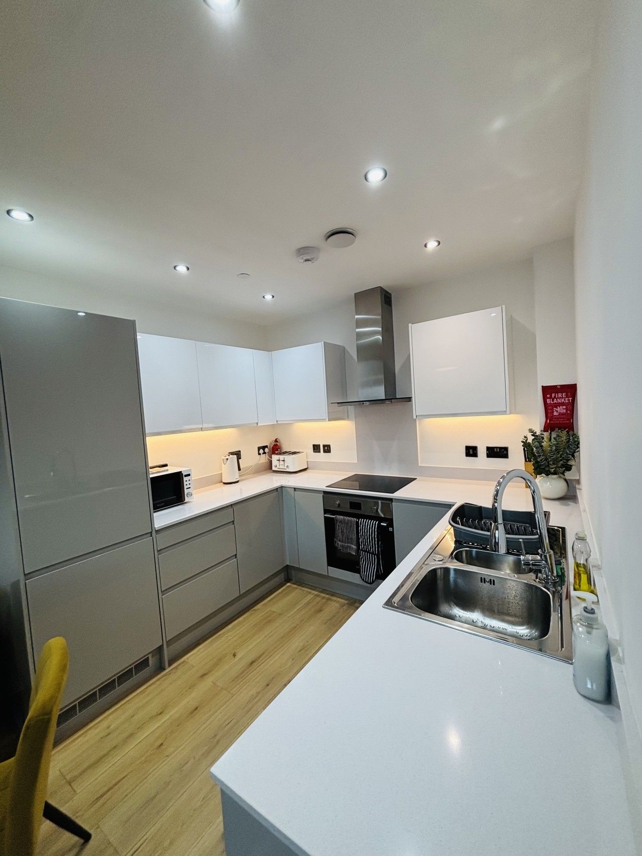 A modern kitchen with white cabinetry, a stainless steel sink, and a built-in oven.
