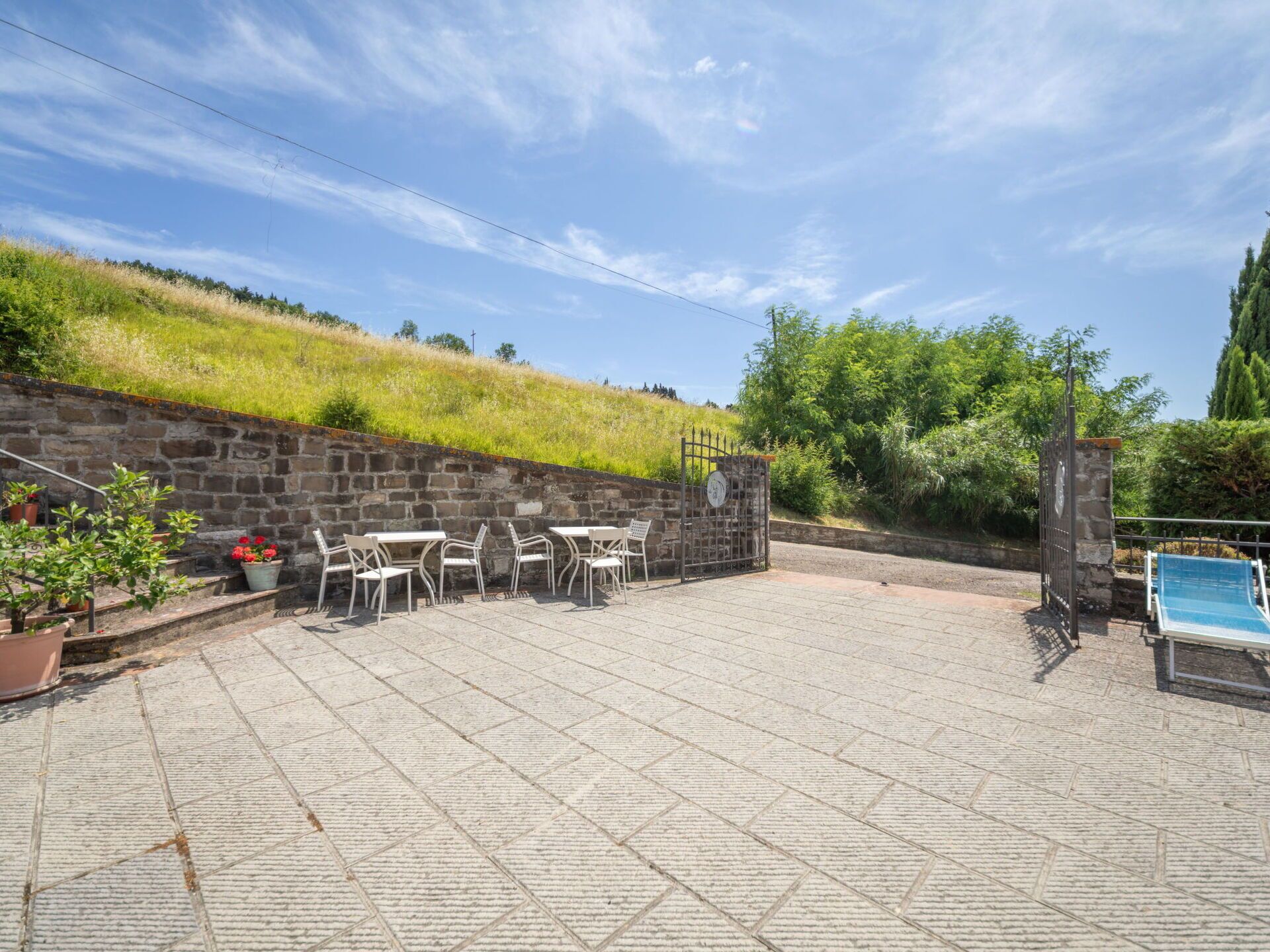Un espace patio doté d’un sol en pierre, de sièges d’extérieur et offrant une vue sur une colline verdoyante.