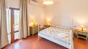 A bedroom with a bed, two bedside tables, a hanging lamp, a window with curtains, and an air conditioning unit. - Beautiful apartment for 4 people with WIFI, pool, A/C, TV, pets allowed and panoramic view (Pontassieve)