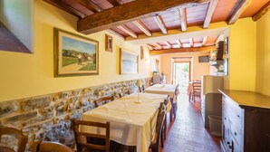 A rustic dining area with stone walls, wooden beams, and a long table with chairs. - Beautiful apartment for 4 people with WIFI, pool, A/C, TV, pets allowed and panoramic view (Pontassieve)