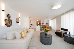 Relax in this stylish living room with a white sofa, coffee table, and dining area.