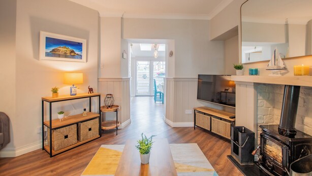 A modern living room with a fireplace, wooden flooring, a TV, and a view through a glass door to an outdoor area. - Cosy Retreat in Galway City Centre (Galway)