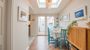 A dining area with a table set for four, a wooden cabinet, and a view through a glass door to an outdoor space. - Cosy Retreat in Galway City Centre (Galway)
