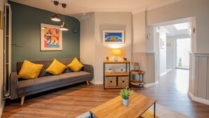 A living room with a gray sofa, yellow cushions, a wooden coffee table, and a lamp on a side table. - Cosy Retreat in Galway City Centre (Galway)