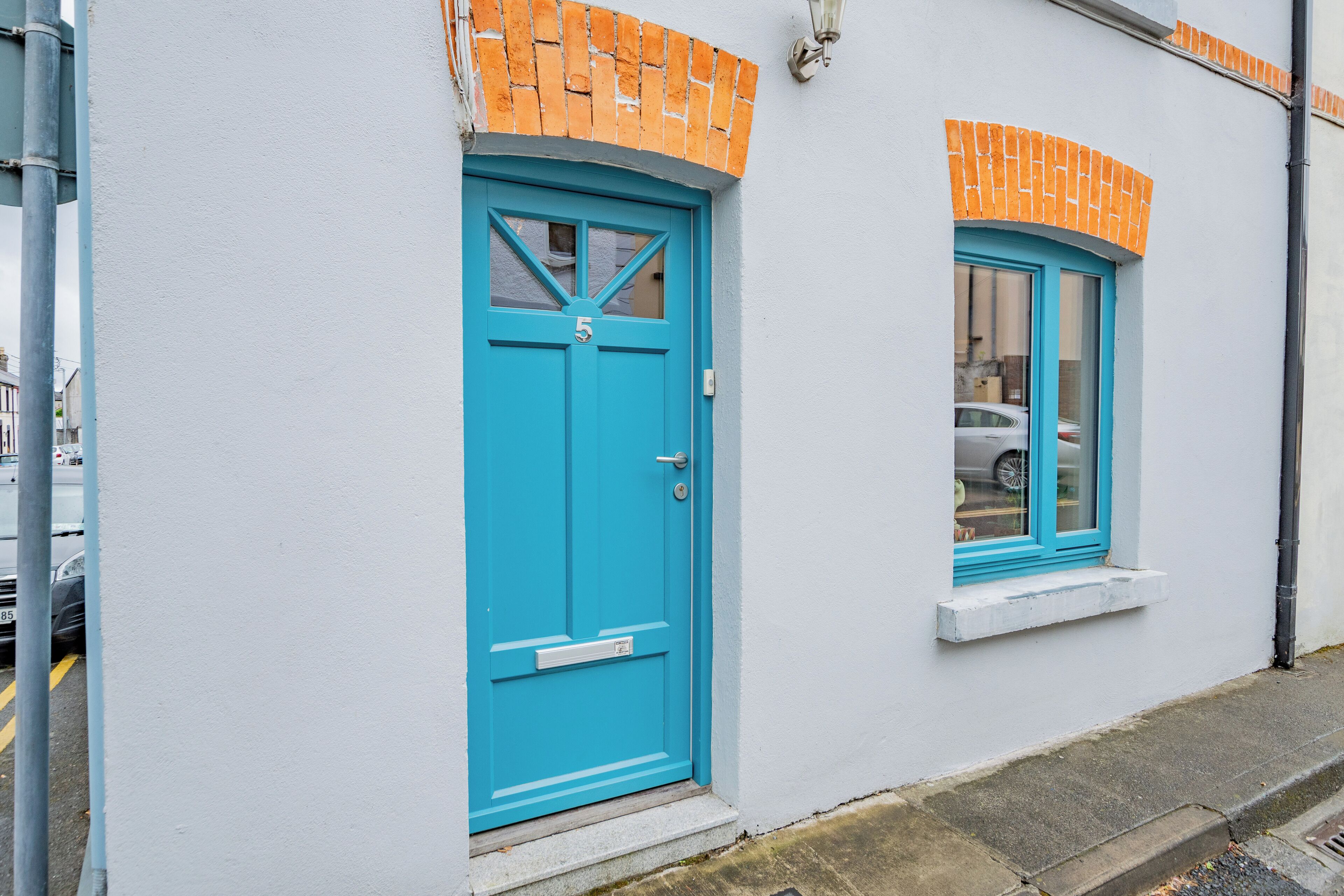 A building with a blue door and window, white walls, and orange brick accents.