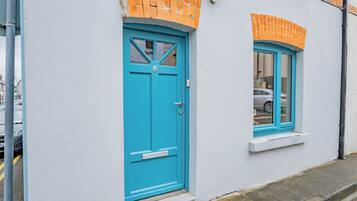 A building with a blue door and window, white walls, and orange brick accents.