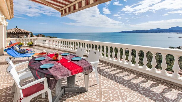 Terraza con mesa lista para comer, con vistas a la costa.