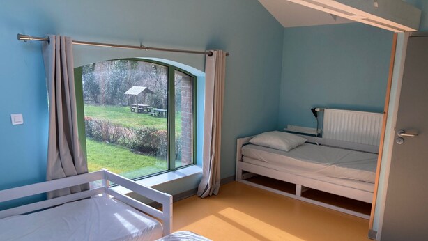 A bedroom with a single bed, a window with curtains, a radiator, and a door. - Ostal Scrignac - Gîte d'étape de la Gare (Scrignac)