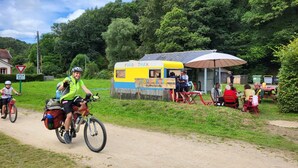 A food truck parked on a dirt path with people sitting at an outdoor table. - Ostal Scrignac - Gîte d'étape de la Gare (Scrignac)