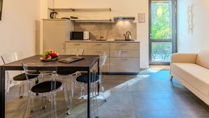 A modern kitchen with a dining area, clear chairs, and a sofa. - Beautiful apartment for 4 people with WIFI, pool, A/C, TV, patio and panoramic view (Dervio)