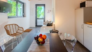 Een moderne keuken met een houten plafond, een eettafel met een schaal fruit, en een bank op de achtergrond.